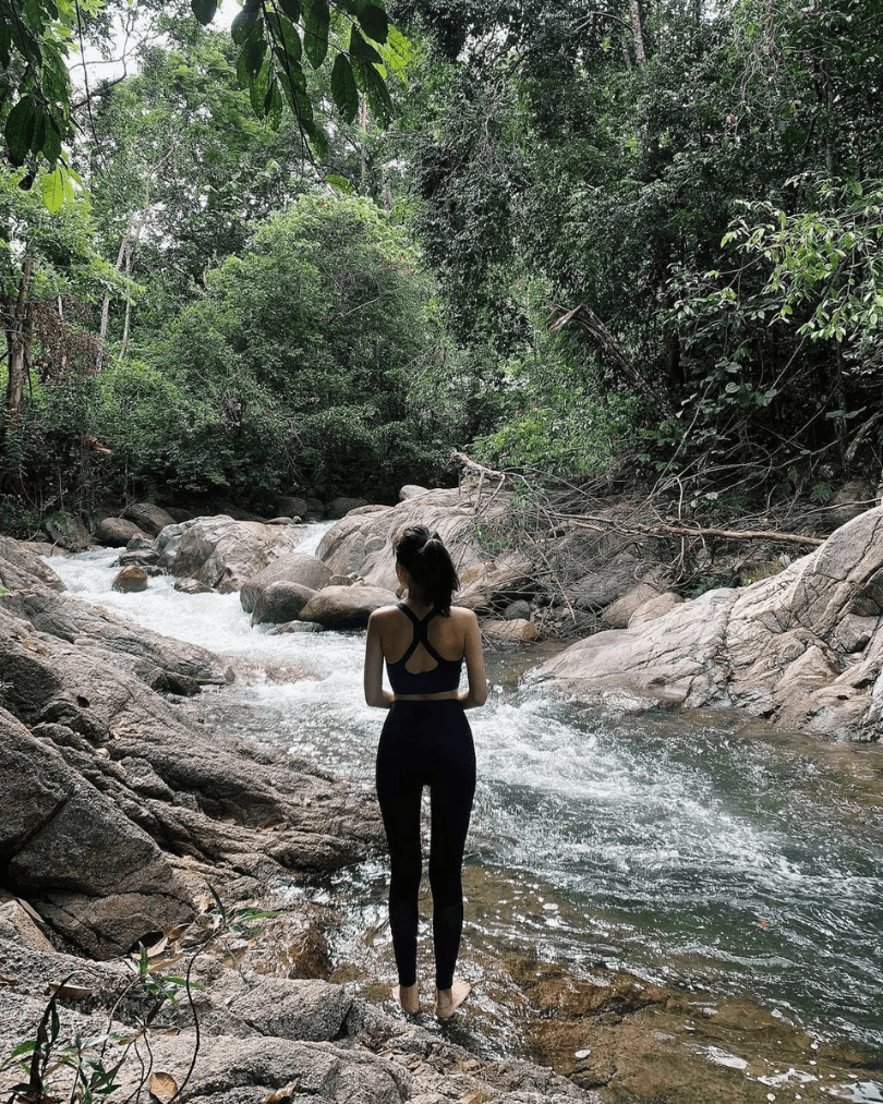 Traveller standing beside a rainforest stream in Malaysia